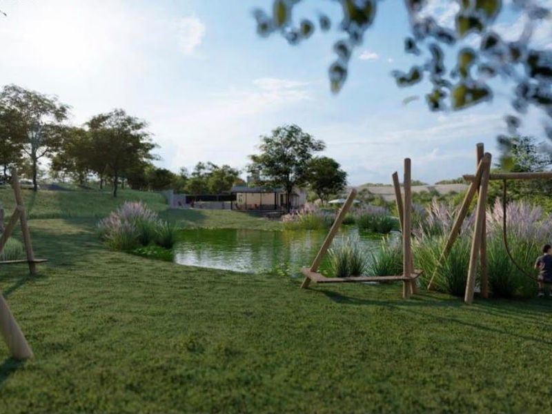 A beautifully landscaped communal garden area featuring a tranquil pond and natural wooden playground structures, offering a serene outdoor space for residents.