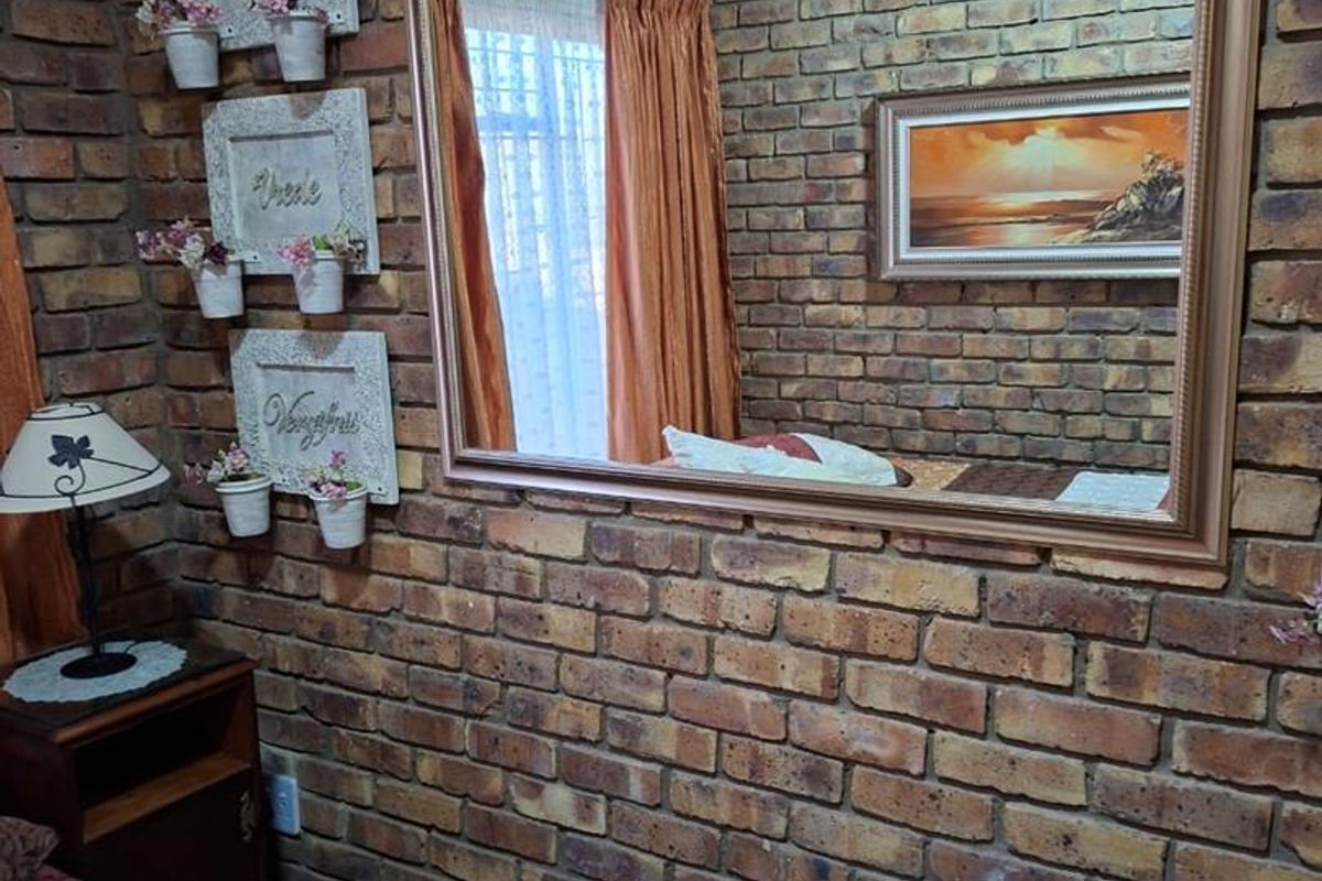A bedroom featuring a prominent exposed brick feature wall, built-in cabinetry, and decorative wall-mounted planters.