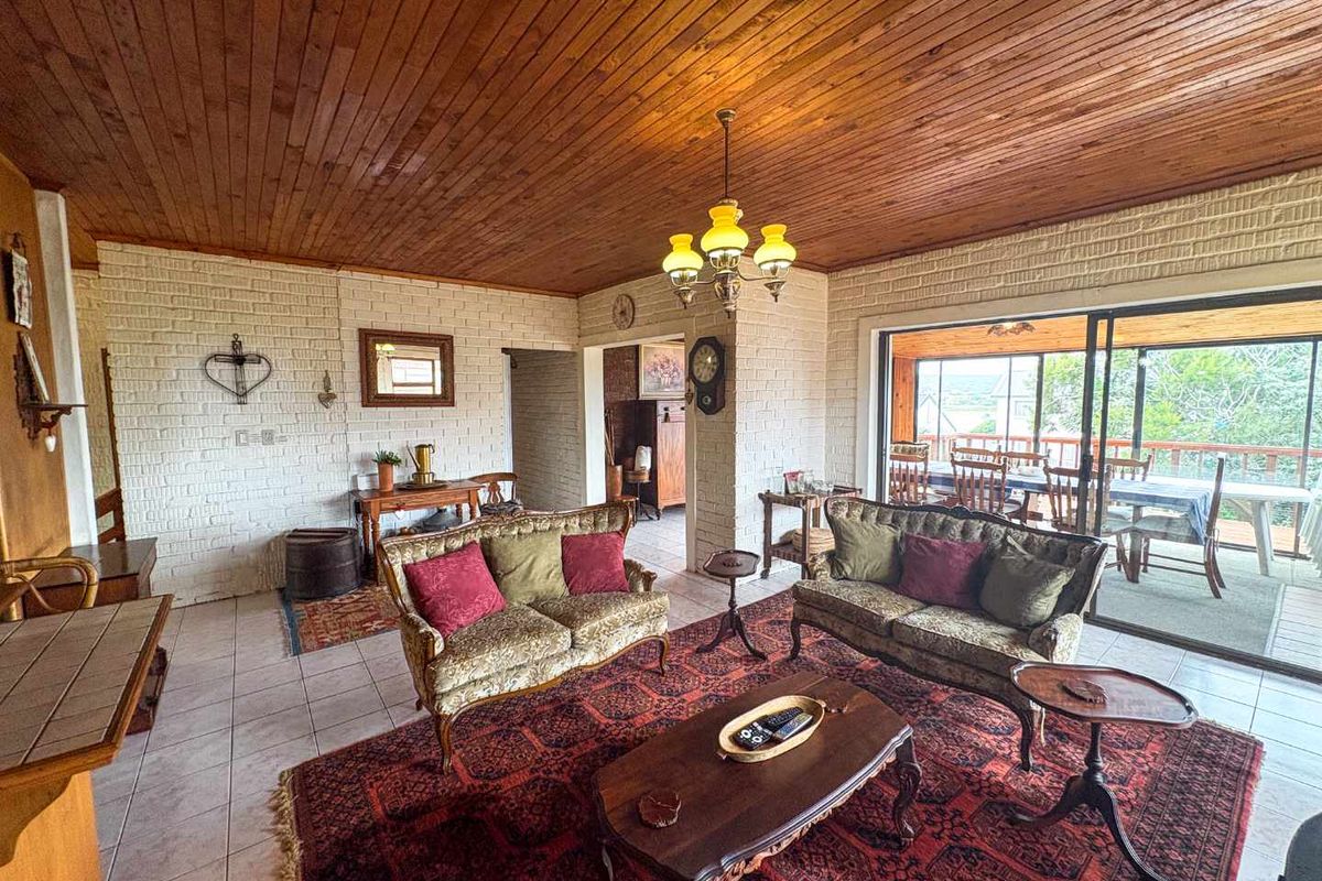Spacious living area featuring a timber-clad ceiling, painted brick walls, and large sliding glass doors opening onto an enclosed patio.