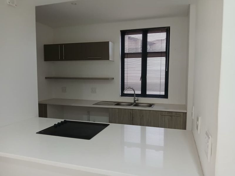 Modern kitchen featuring sleek cabinetry, stone countertops, a built-in hob, and a stainless steel double sink with a window view.