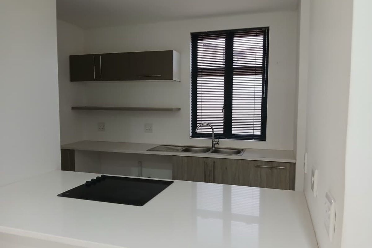 Modern kitchen featuring sleek cabinetry, stone countertops, a built-in hob, and a stainless steel double sink with a window view.