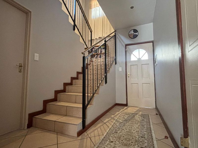 Entrance hall featuring a tiled staircase with metal balustrade and a panelled front door, providing a functional and welcoming transition space.