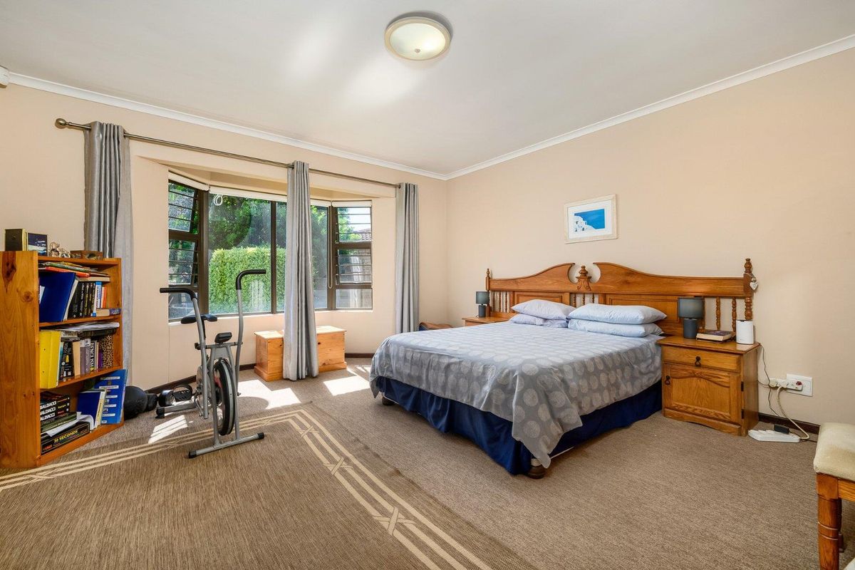 Spacious bedroom featuring a large bay window, neutral wall tones, and fitted carpet flooring.