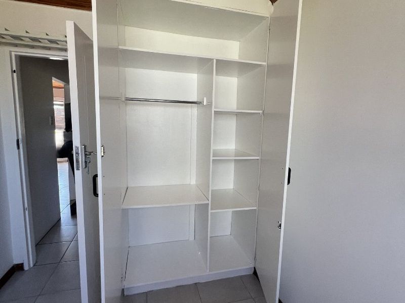 A bedroom featuring a built-in wardrobe, tiled flooring, and a timber-paneled ceiling.