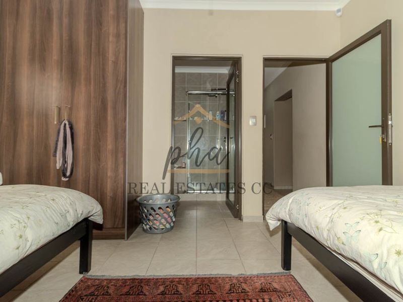 A bedroom featuring tiled flooring, a built-in wardrobe, and direct access to an en-suite bathroom.