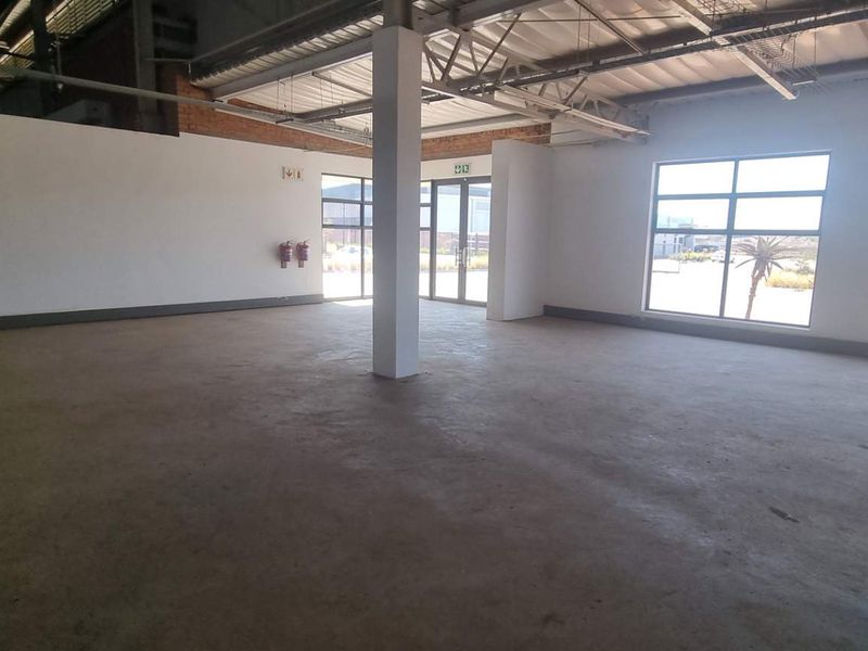 Spacious open-plan industrial unit featuring polished concrete floors, exposed steel roof structure, and large windows providing ample natural light.