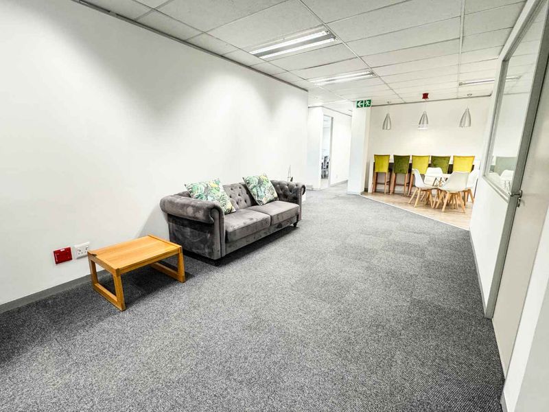 Open-plan office space featuring carpeted flooring, suspended ceilings with recessed lighting, and a glass partition wall, suitable for a professional business environment.