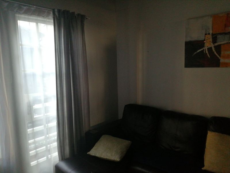 A dimly lit living room area featuring a window with curtains, providing natural light to the space.