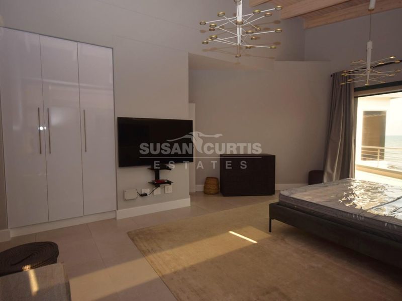 Spacious bedroom featuring built-in wardrobes, tiled flooring, and direct access to a balcony with scenic views.