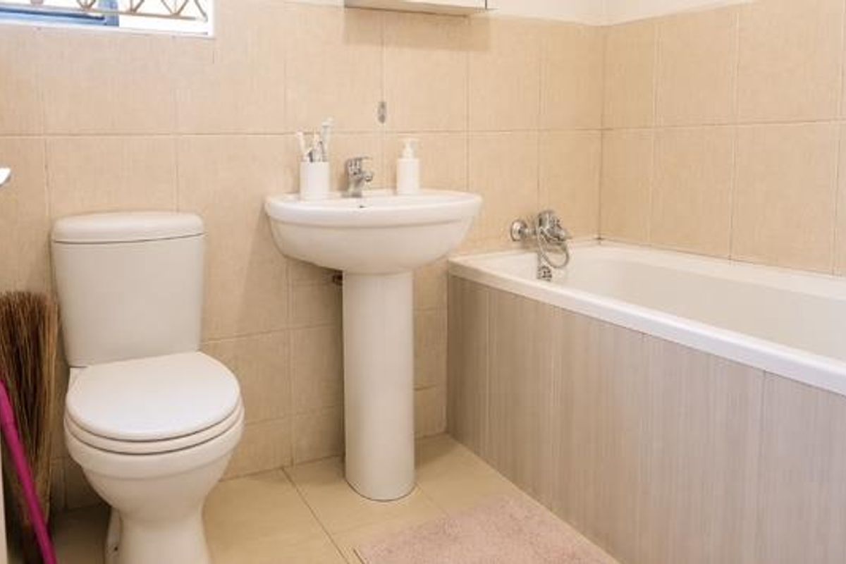 A functional bathroom featuring a pedestal washbasin, a standard toilet, and a bathtub with tiled wall finishes.