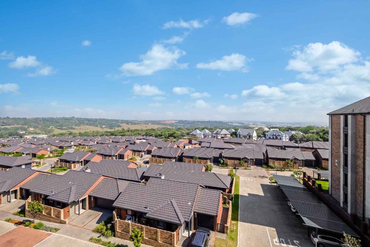 An elevated aerial view of a retirement village complex featuring multiple residential units with tiled roofs, paved driveways, and covered parking bays.