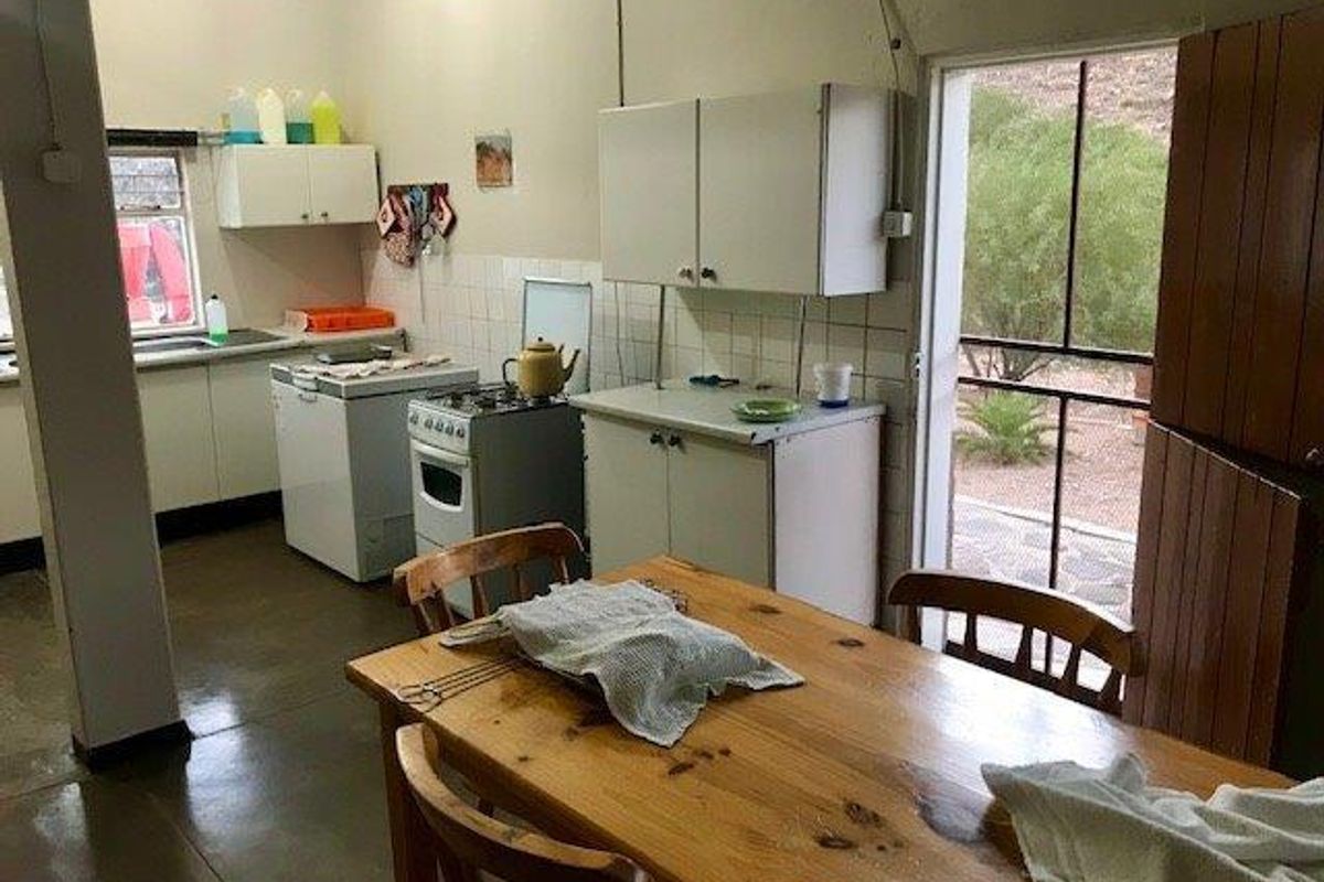 A functional farm-style kitchen featuring basic cabinetry, a freestanding stove, and direct access to the outdoor area.