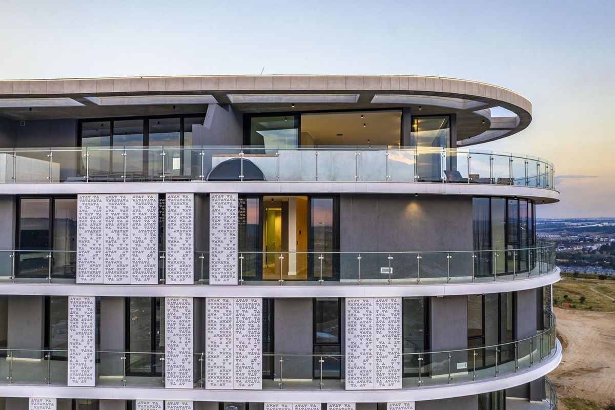 Modern penthouse exterior featuring expansive glass balconies, decorative privacy screens, and sleek architectural lines with panoramic views.