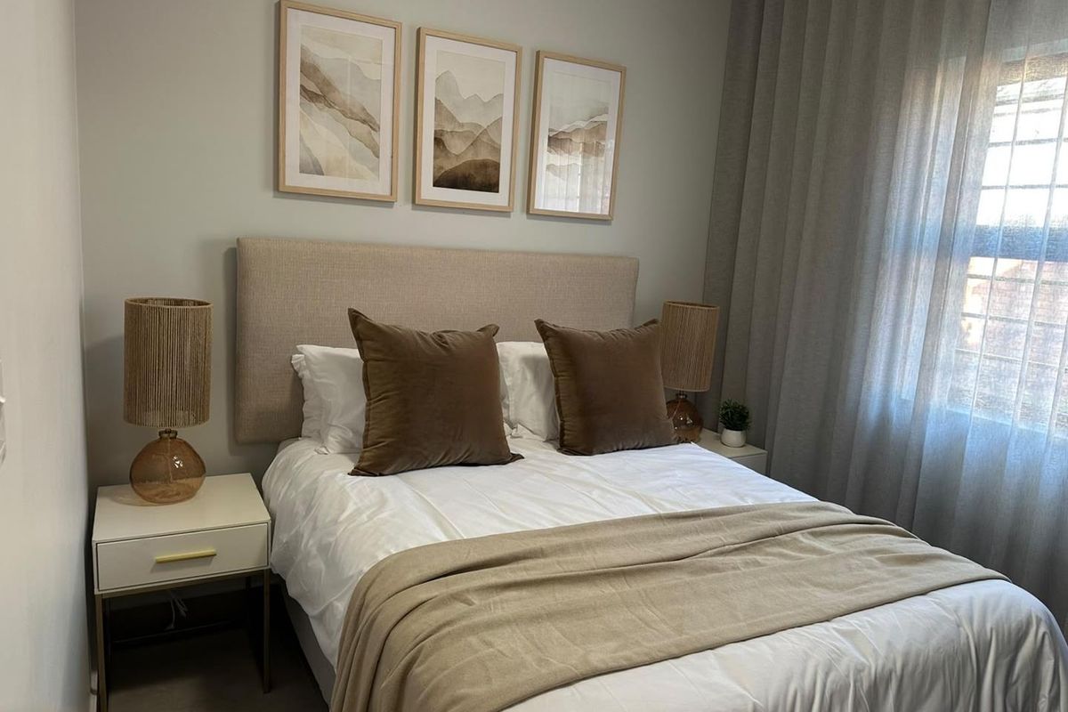 A well-maintained bedroom featuring neutral wall tones, floor-to-ceiling curtains, and a clean, modern aesthetic.