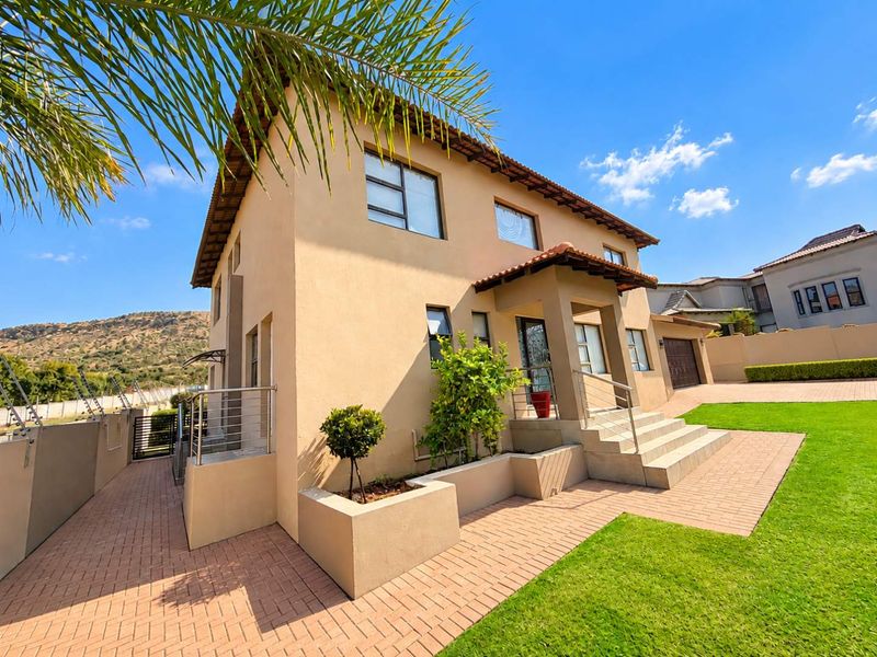 A well-maintained double-story residential home featuring a paved entrance, concrete stairs with stainless steel railings, and a neat front garden.