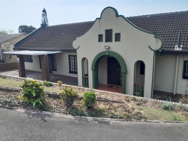 Front elevation of a house featuring a distinctive arched entrance, tiled roof, and a covered porch area with brick pillars.