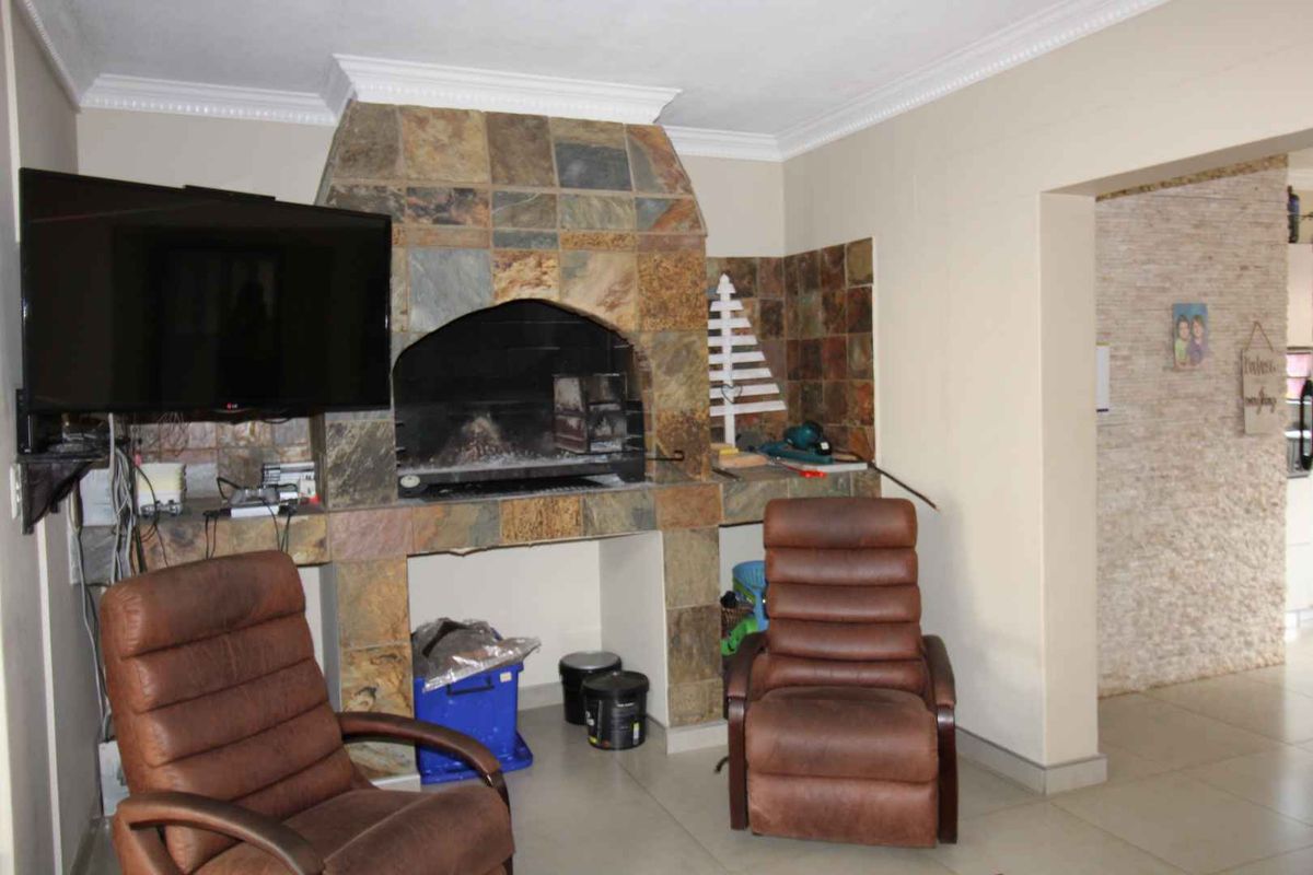 Indoor entertainment area featuring a built-in stone fireplace and tiled flooring, providing a cozy space for relaxation.
