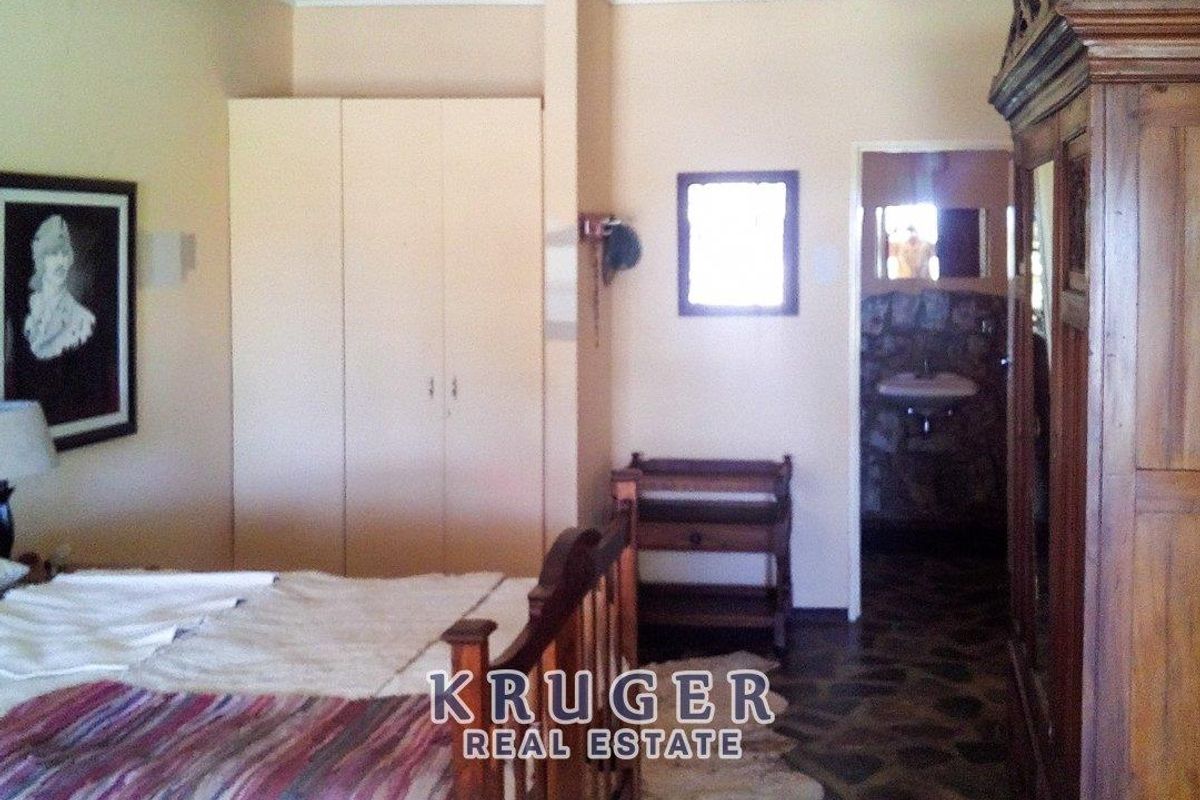 A bedroom featuring built-in cupboards and an en-suite bathroom with stone-clad walls and tiled flooring.