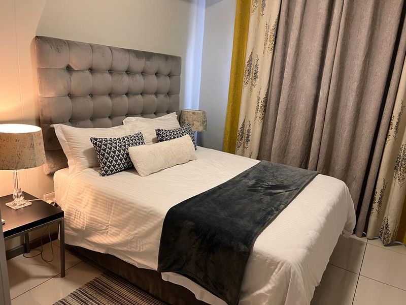 A well-maintained bedroom featuring neutral tiled flooring and a modern upholstered headboard, creating a comfortable and inviting sleeping space.