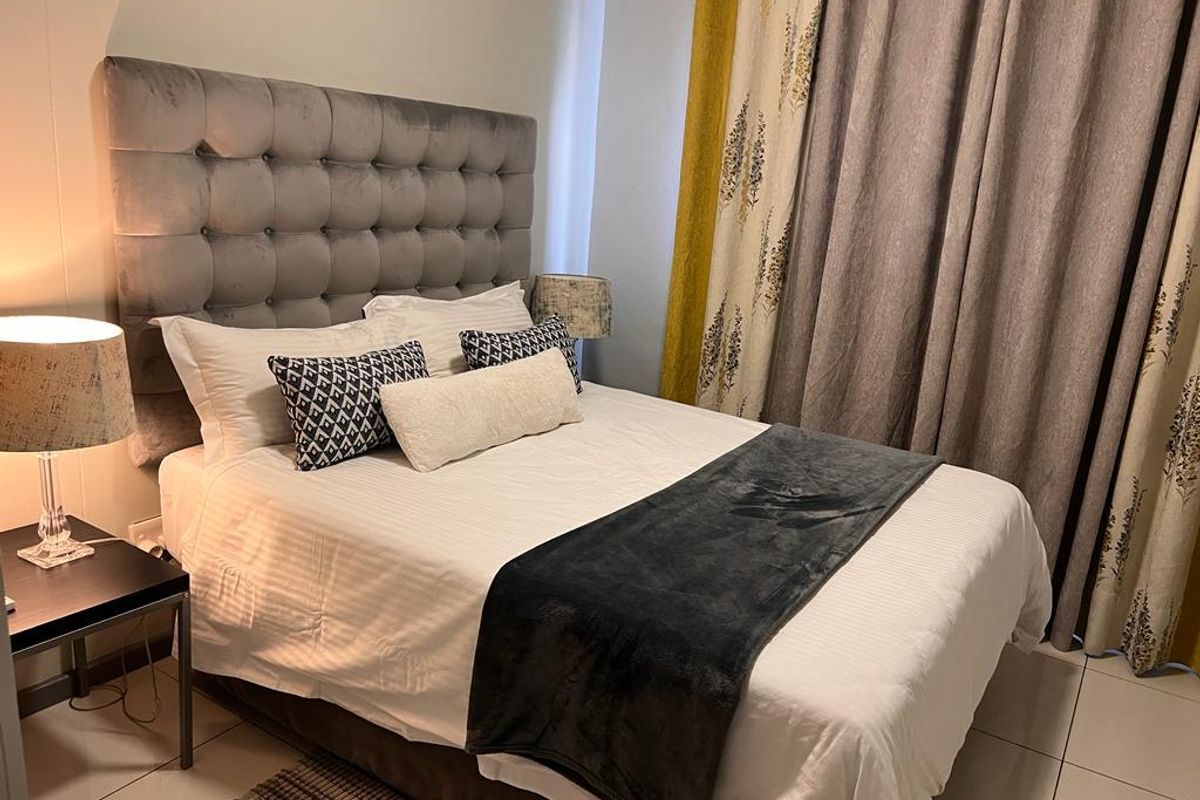 A well-maintained bedroom featuring neutral tiled flooring and a modern upholstered headboard, creating a comfortable and inviting sleeping space.