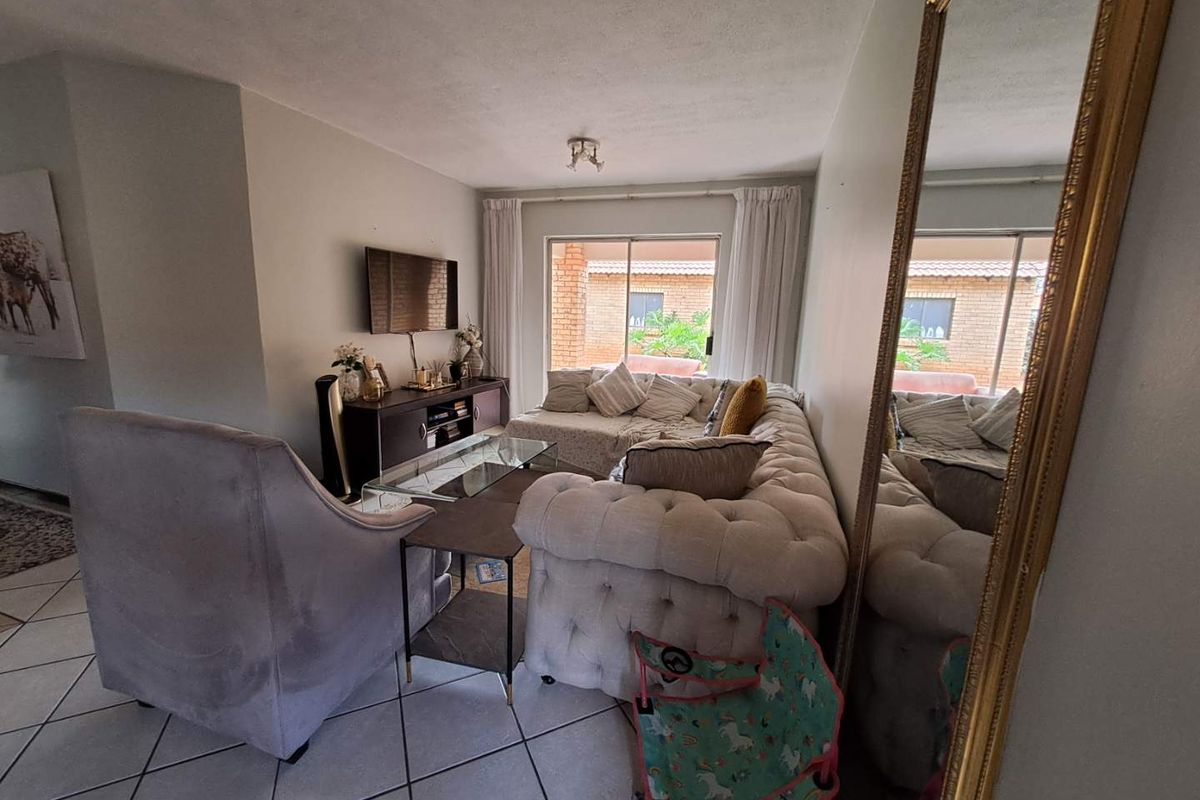 A comfortable living room featuring tiled flooring and a large sliding glass door that provides natural light and access to the exterior.