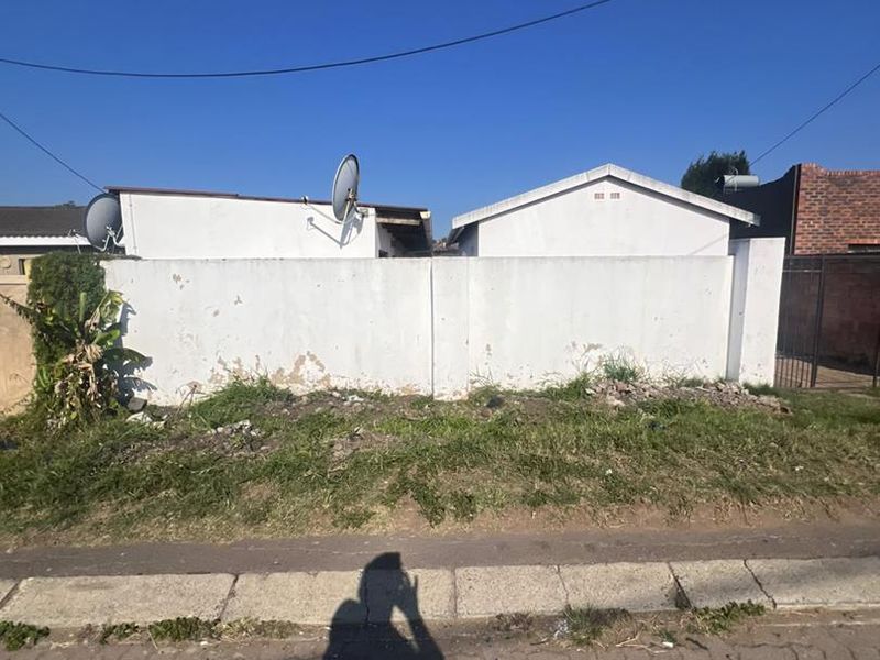 Street view of the property boundary wall showing signs of wear and weathering, with visible satellite dishes mounted on the structure behind.