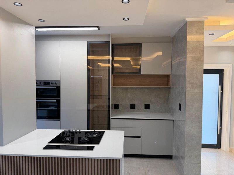 Modern kitchen featuring sleek cabinetry, stone countertops, a built-in double oven, and a gas hob, finished with contemporary tiling and recessed lighting.