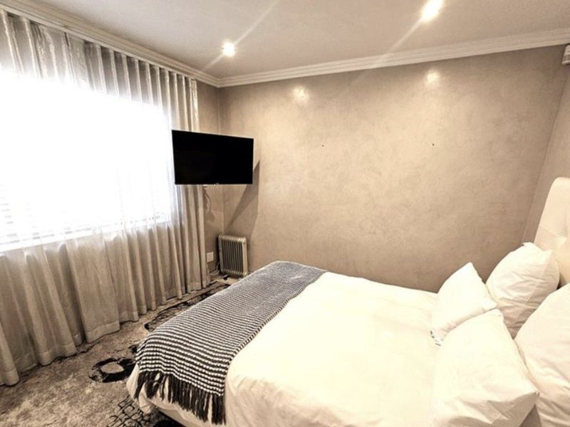 A well-maintained bedroom featuring recessed ceiling lighting, crown molding, and neutral wall finishes, creating a comfortable and inviting sleeping space.