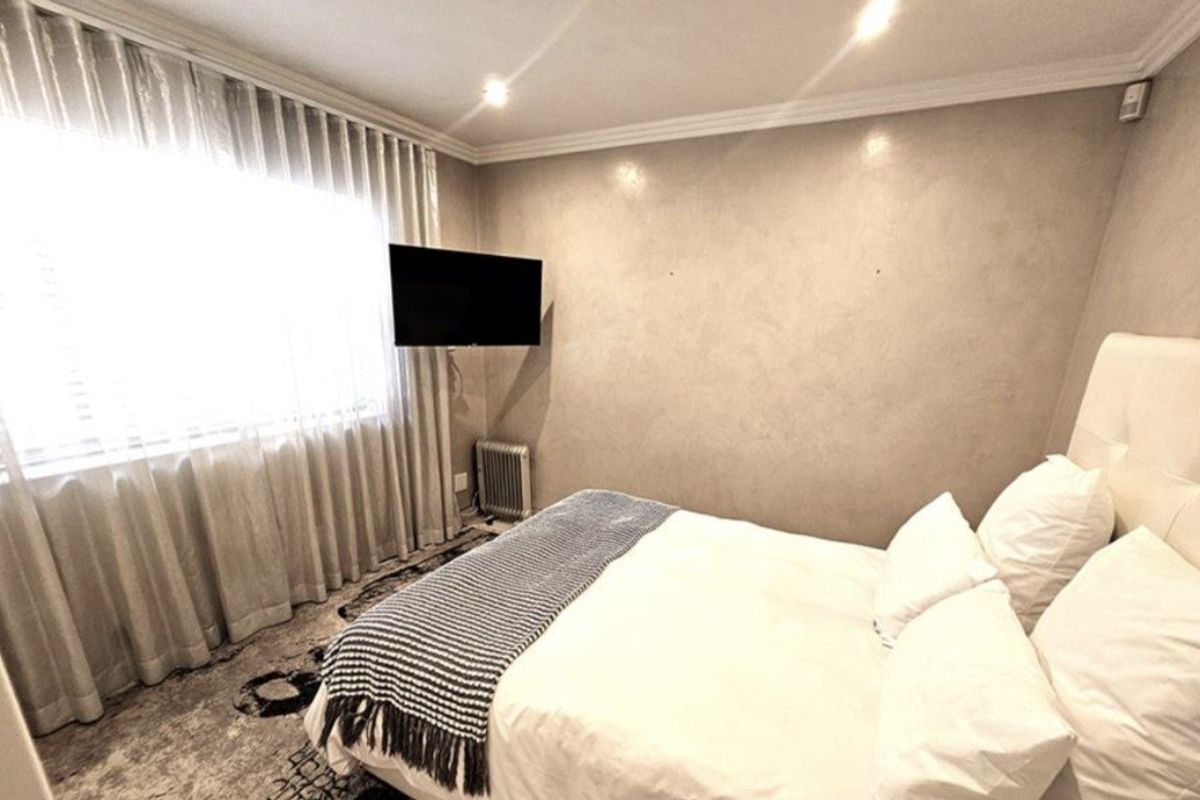 A well-maintained bedroom featuring recessed ceiling lighting, crown molding, and neutral wall finishes, creating a comfortable and inviting sleeping space.