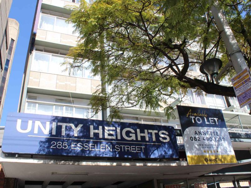 Exterior view of the Unity Heights apartment building facade featuring balconies and prominent street-level signage.
