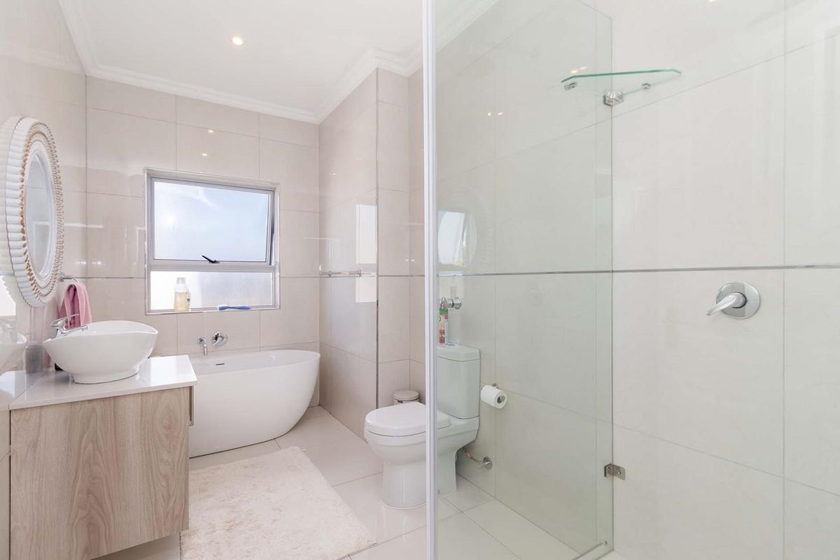 Modern bathroom featuring a freestanding bathtub, glass-enclosed shower, vanity with vessel sink, and neutral floor-to-ceiling tiling.