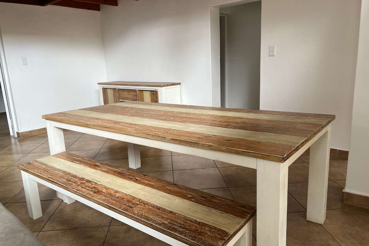 Dining area featuring ceramic floor tiles and exposed timber ceiling beams, providing a neutral and functional space for meals.
