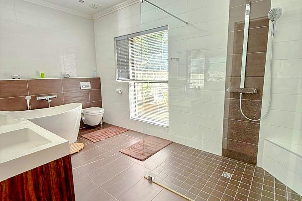 Modern bathroom featuring a spacious walk-in shower with glass screen, a sleek freestanding bathtub, wall-mounted toilet, and a contemporary double vanity.