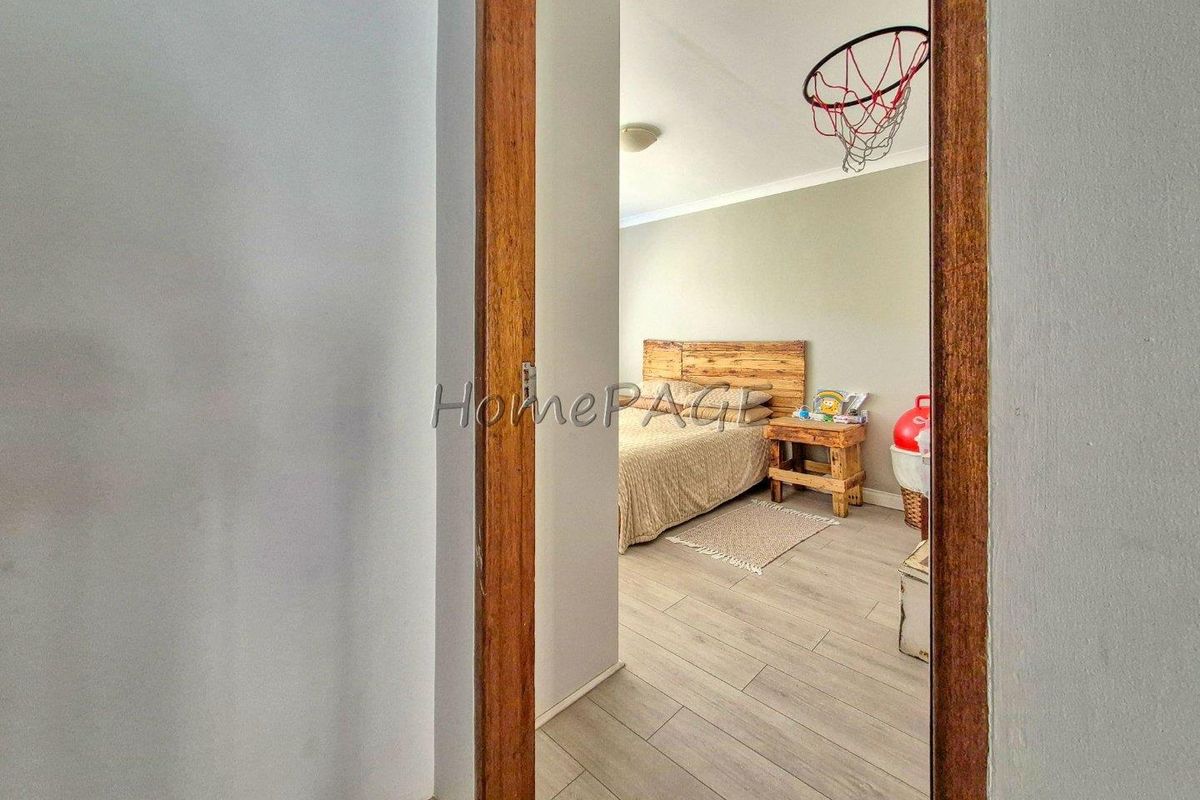 A view through a timber door frame into a bedroom featuring light-toned laminate flooring and neutral wall finishes.