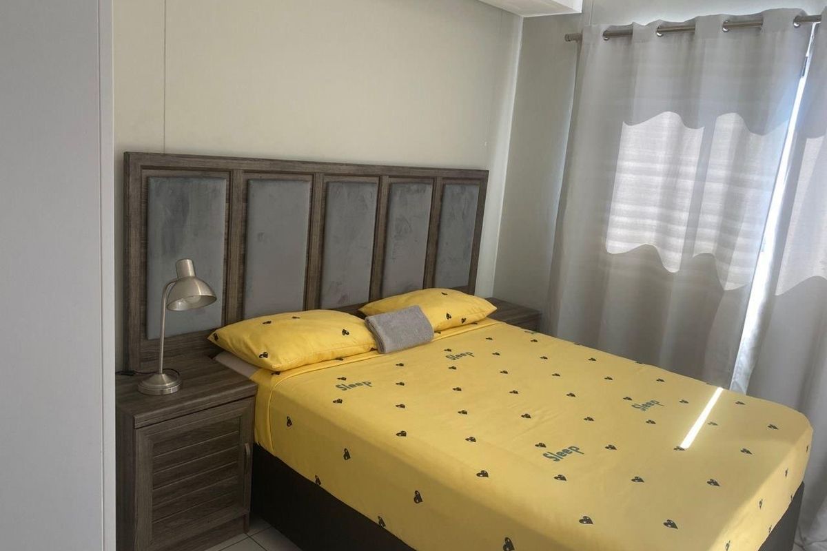 A bedroom featuring neutral wall finishes, tiled flooring, and a window with fitted curtain tracks.