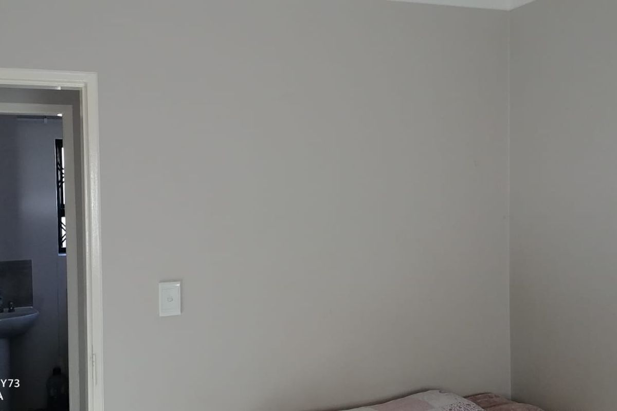 A neutral-toned bedroom interior featuring a doorway leading to an adjacent bathroom.