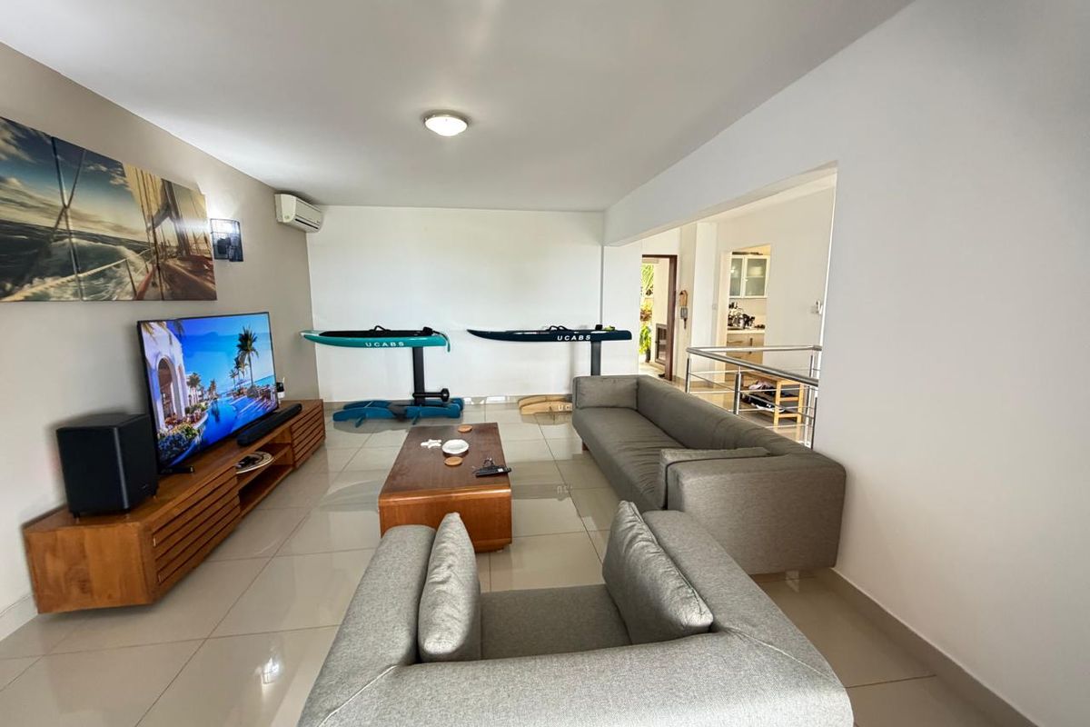 Spacious living area featuring tiled flooring, split-system air conditioning, and an open-plan layout connecting to the kitchen and hallway.