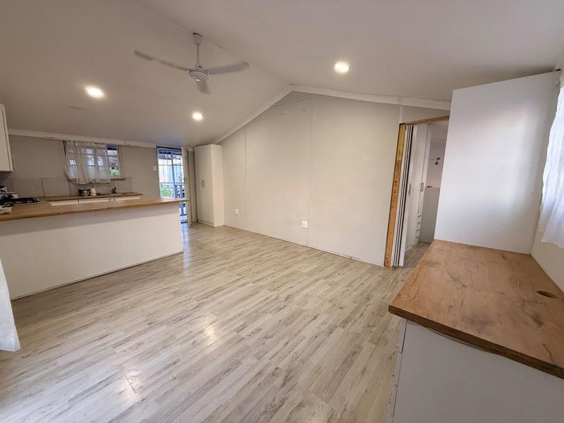 Spacious open-plan living area featuring laminate flooring, recessed lighting, and a functional kitchen with timber countertops, ready for personalization.