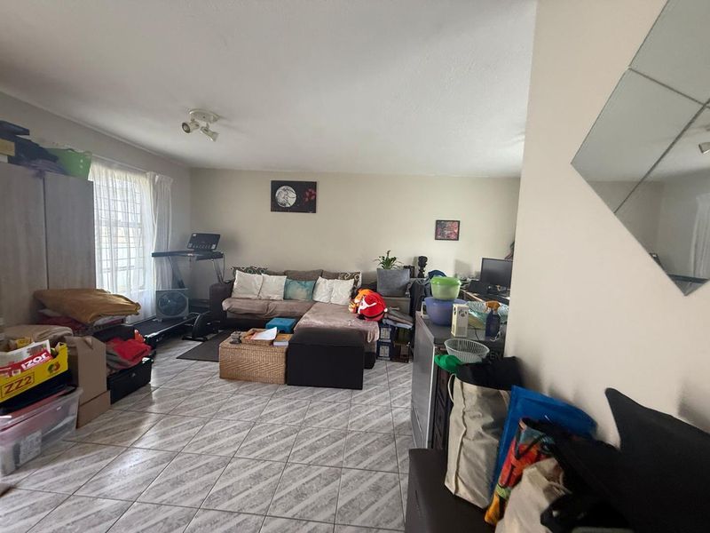 A spacious living area featuring tiled flooring and neutral wall finishes, offering a versatile layout for comfortable daily living.