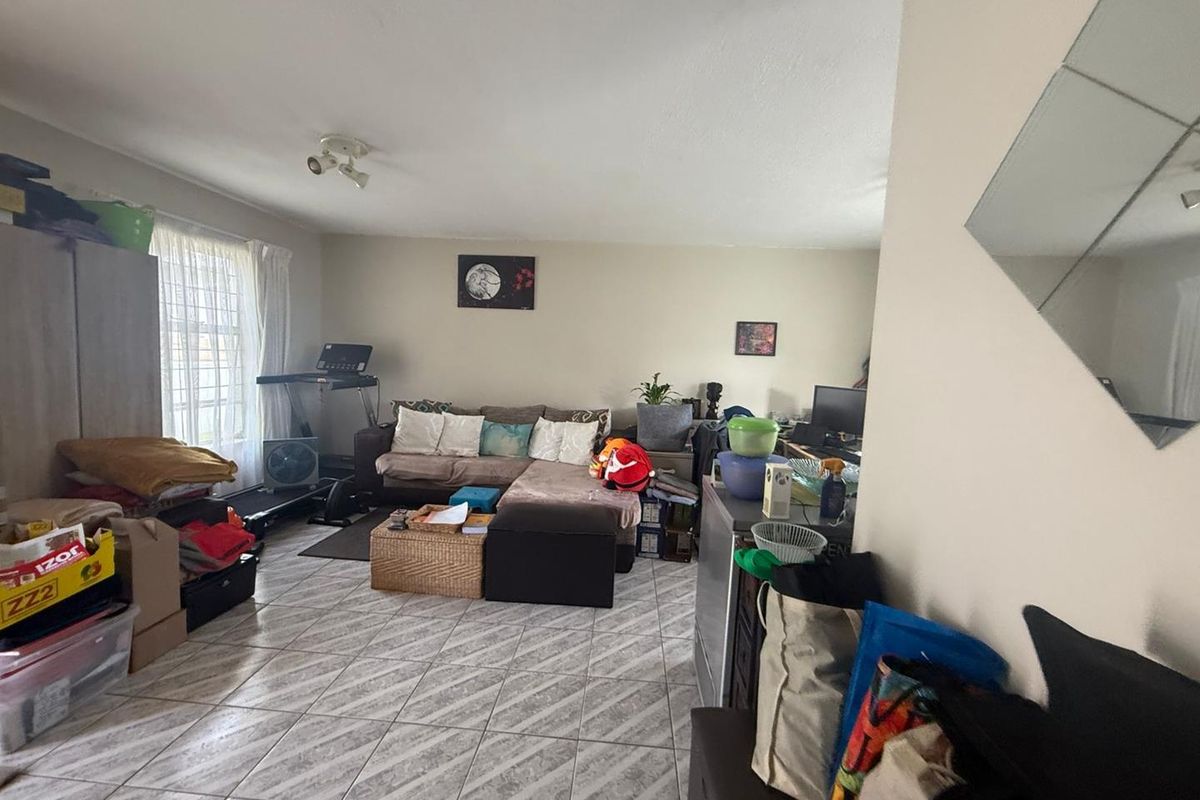 A spacious living area featuring tiled flooring and neutral wall finishes, offering a versatile layout for comfortable daily living.