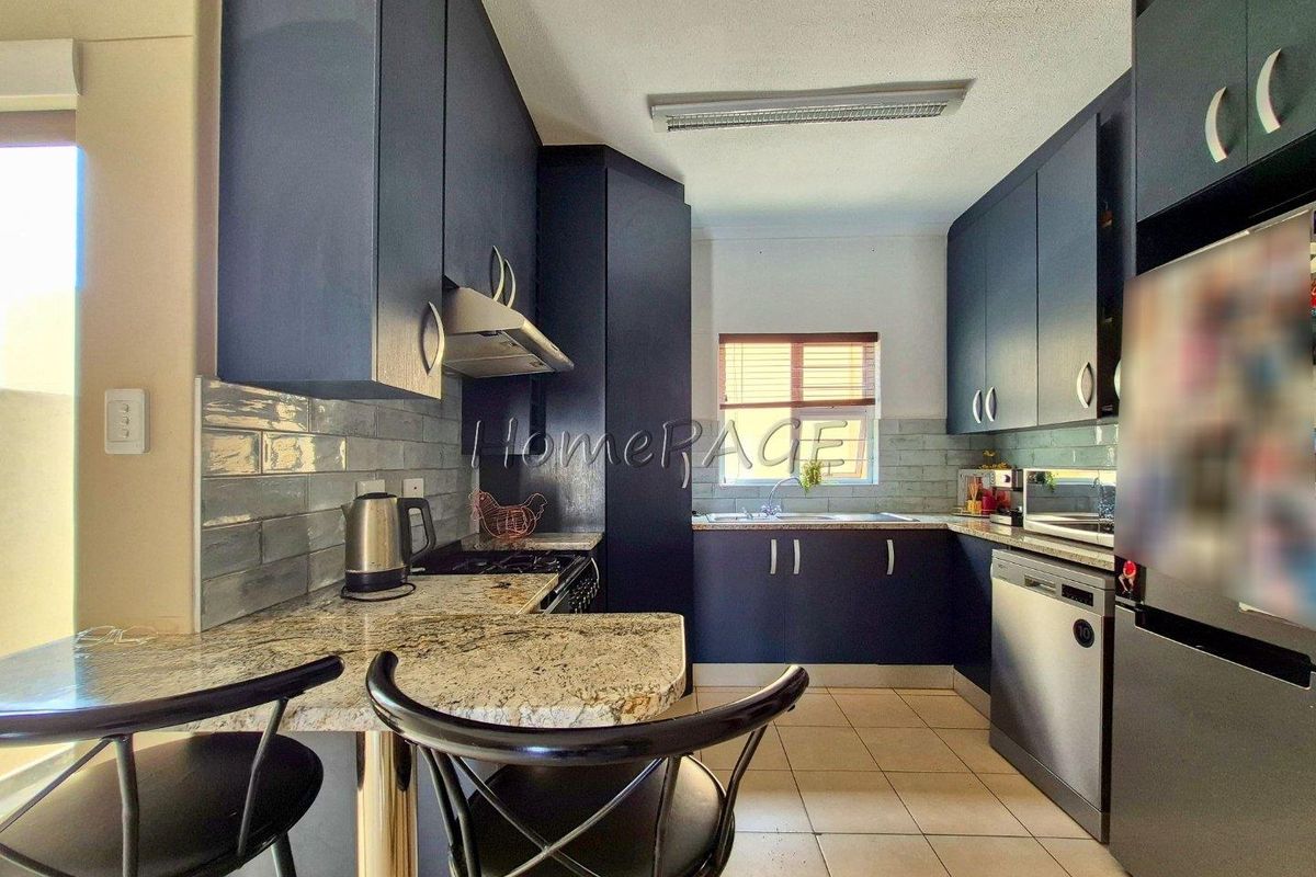 A modern kitchen featuring dark blue cabinetry, granite countertops, a tiled backsplash, and integrated stainless steel appliances.
