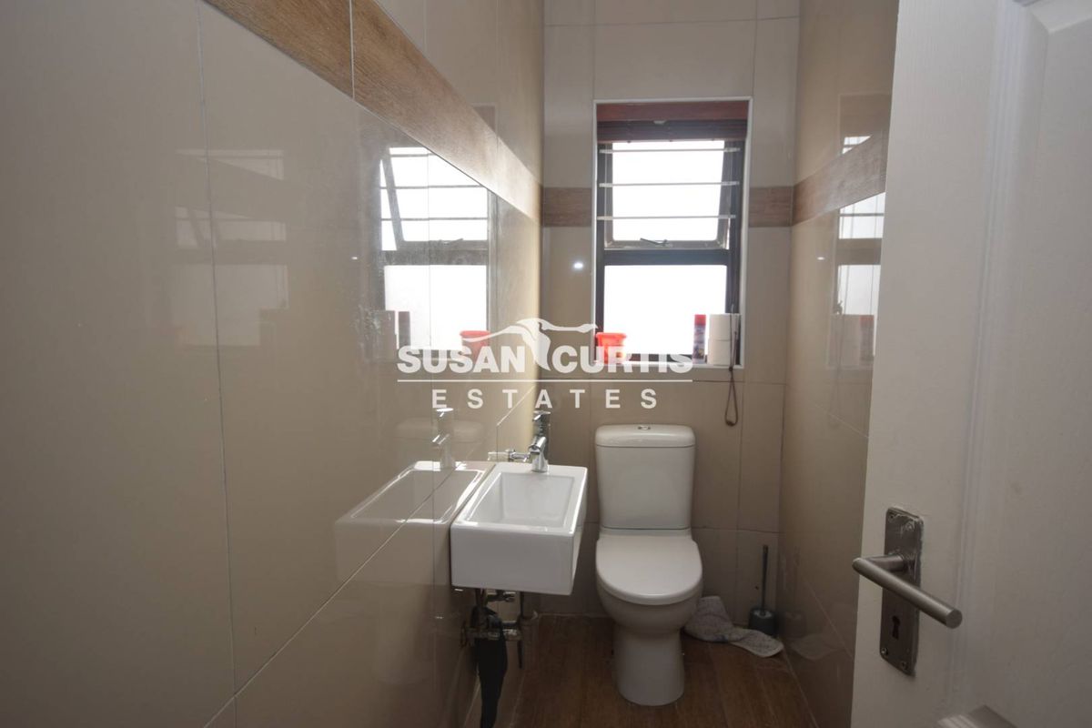 A compact, modern guest bathroom featuring floor-to-ceiling wall tiles, a wall-mounted basin, and a standard toilet.
