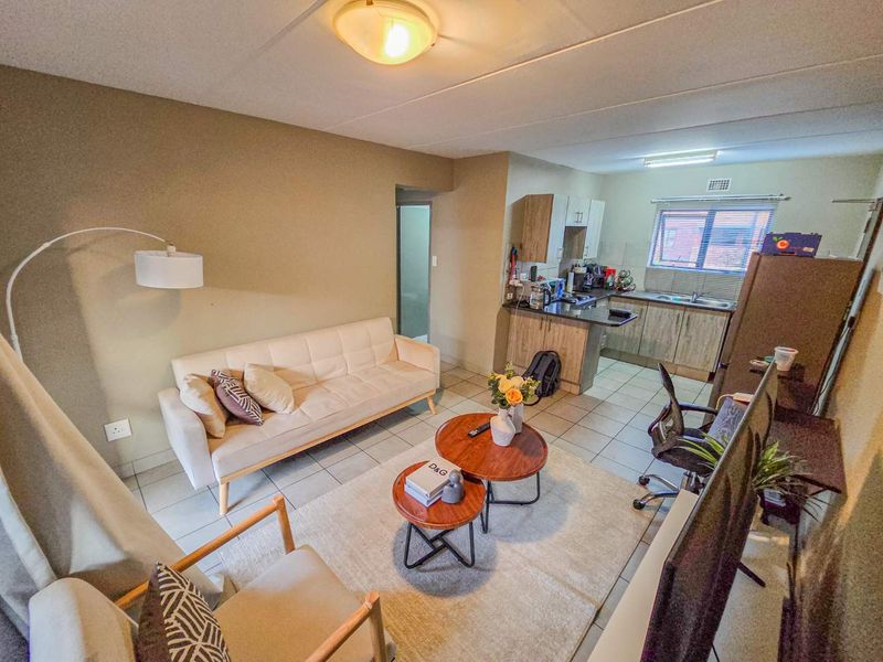 Open-plan living area featuring tiled floors and a functional kitchen with built-in cabinetry and laminate countertops.