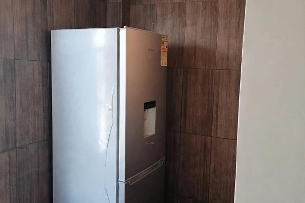 A functional kitchen corner featuring full-height dark wood-look wall tiling and neutral floor tiles, providing a clean and durable workspace.