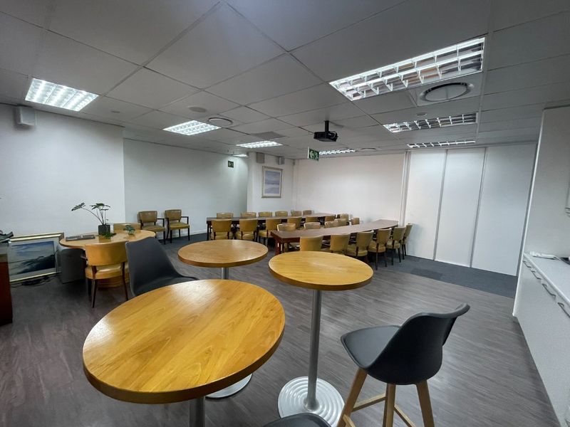 A spacious office area featuring suspended ceilings, recessed lighting, and durable laminate flooring, suitable for meetings or collaborative workspace.