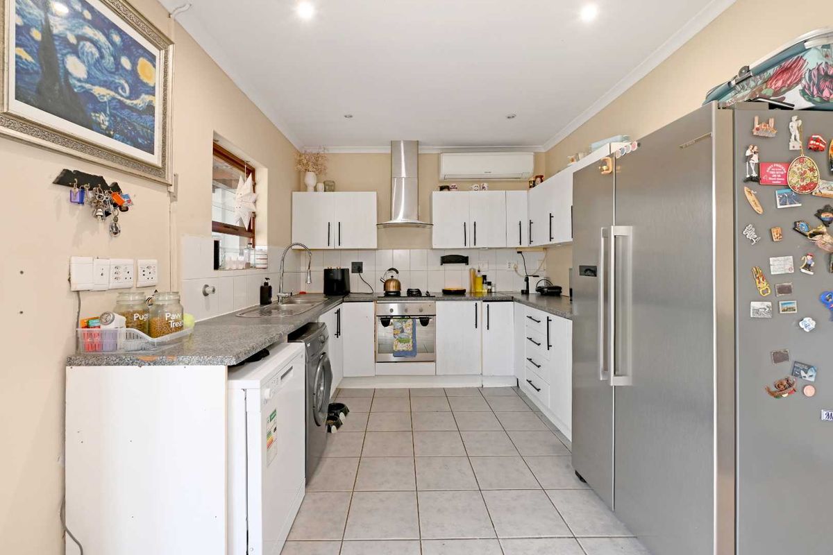 A functional kitchen featuring white cabinetry, stone countertops, stainless steel appliances, and tiled flooring with integrated air conditioning.