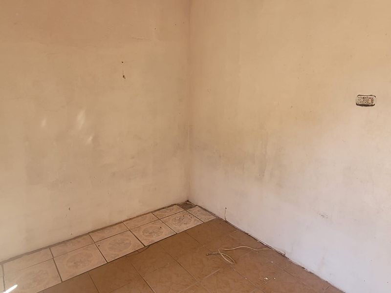 An empty room corner featuring worn ceramic floor tiles and stained wall surfaces, requiring cosmetic refurbishment and maintenance.