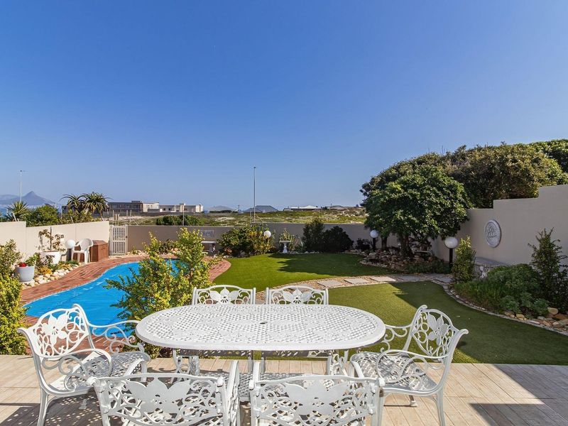 Outdoor entertainment area featuring a swimming pool, tiled patio, and landscaped garden with artificial lawn and boundary walling.