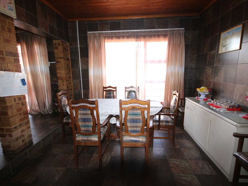 Dining room featuring dark tiled walls, tiled flooring, and a timber ceiling, with a sliding glass door providing natural light.