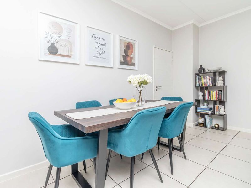 A bright and well-maintained dining area featuring neutral walls, tiled flooring, and coved ceiling details.